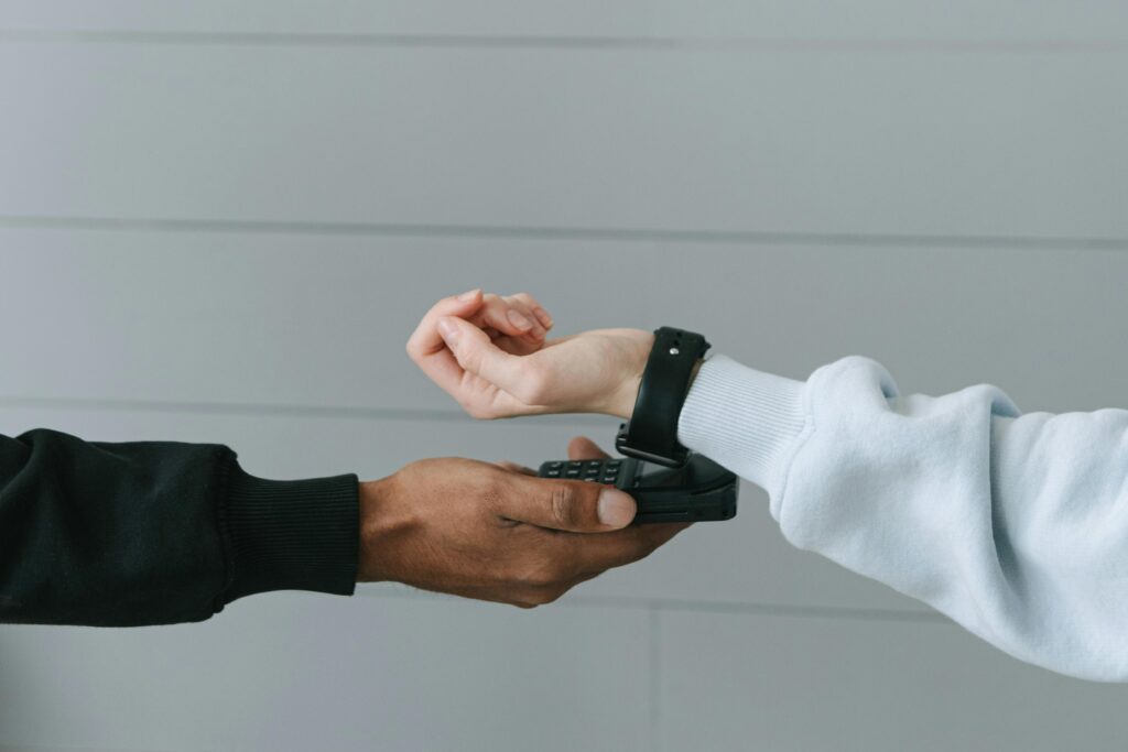 A person using a smartwatch for a secure contactless payment on a portable terminal indoors.